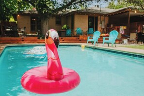A swimming pool with a pink inflatable flamingo float. - Historic Sayles Ranch- Huge Deck + Pool! (Abilene)
