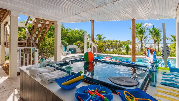 Un espace piscine comprenant un jacuzzi, des chaises longues et un coin salon couvert avec des parasols.