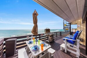 Une terrasse avec une table dressée pour les repas, un barbecue et un fauteuil de relaxation.