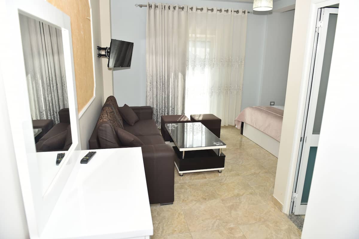 A modern living room with a sofa, a coffee table, and a TV mounted on the wall.