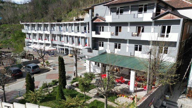 Een hotel met meerdere verdiepingen, een binnenplaats, terraszitplaatsen en een zichtbare ingang.