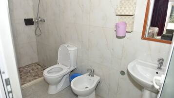 Ein Badezimmer mit Toilette, Bidet, Waschbecken und Dusche.
