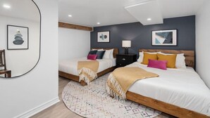 Una camera da letto moderna con due letti, uno specchio rotondo e opere d'arte alle pareti.