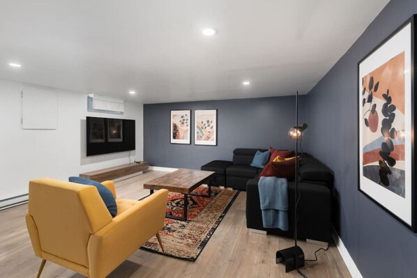 A modern living room with a sofa, a yellow armchair, a coffee table, and a TV mounted on the wall.