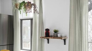 A modern kitchen with a white countertop, a hanging plant, and a red kettle on a wooden shelf. - Unique Old, Montreal Patio & Paid Parking 10 Guest (Montréal)