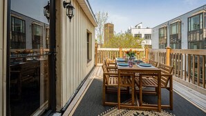 A balcony with a wooden table set for dining, a glass door, and a view of the cityscape. - Unique Old, Montreal Patio & Paid Parking 10 Guest (Montréal)