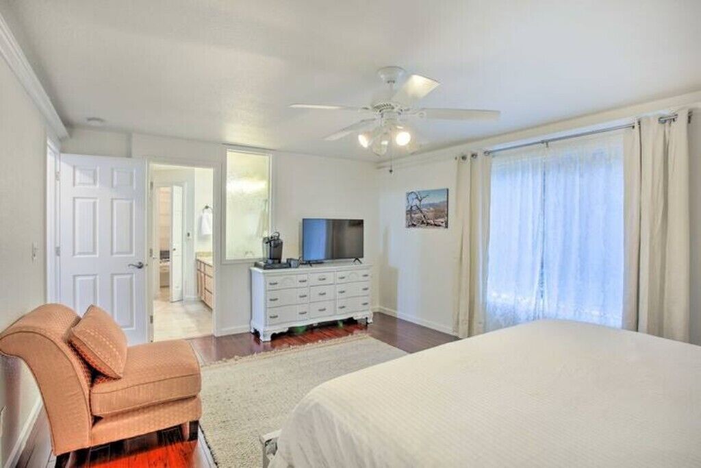 Un dormitorio con cama, cómoda, televisor y ventilador de techo.