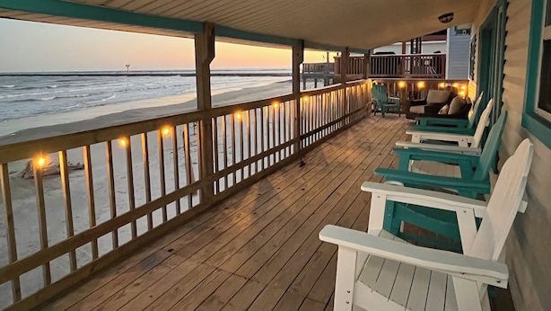 A wooden deck with a railing overlooking the ocean, featuring several chairs and a table. - Pedestrian Beach Front 3- bedroom house in Surfside Beach (Surfside Beach)