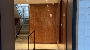 Un interior moderno con suelo de mármol, una escalera y una pared con textura decorativa.