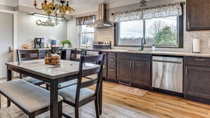 A modern kitchen with dark wood cabinets, a large island with seating, a built-in oven, and a window with a view of trees. - 7 Mi to Depot District: Pet-Friendly w/ Fire Pit (Richmond)