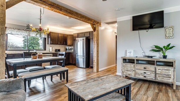 A modern kitchen with wooden beams, a dining area with a bench, and a TV mounted on the wall. - 7 Mi to Depot District: Pet-Friendly w/ Fire Pit (Richmond)