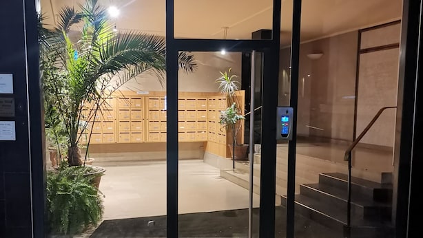 Entrada de hotel com porta de vidro, escada e balcão de recepção.