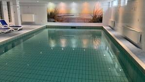 A swimming pool with tiled walls and a mural of a sunset.