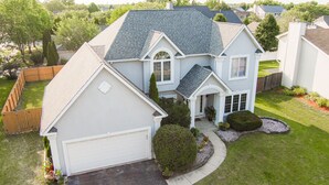A two-story house with a garage, a covered front porch, and a well-maintained lawn.