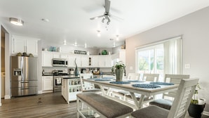 A modern kitchen with white cabinets, stainless steel appliances, and a dining area with a table set for four.