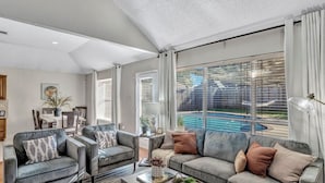 A spacious living room with a large window, a pool, and a dining area. - Splash & Play Hideaway: Pool House + Game Room/Gym (Lewisville)
