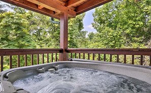 A hot tub under a wooden pergola with a view of lush green trees. - Log Cabin w/ Panoramic Mountain Views! (Sevierville)