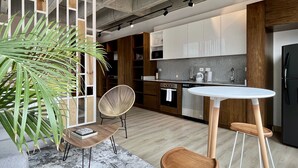 A modern kitchen with wooden cabinets, a white countertop, and a black refrigerator. - Canvas by Wynwood House (Bogotá)