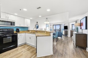 A modern kitchen with white cabinetry, a black stove, and a blue tiled backsplash. - Family Oceanfront Condo Located in  North end of Myrtle Beach! (Myrtle Beach)