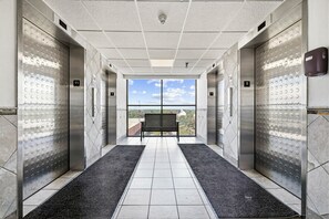 A modern elevator interior with a clear view to the outside, a bench, and a tiled floor. - Family Oceanfront Condo Located in North end of Myrtle Beach! (Myrtle Beach)