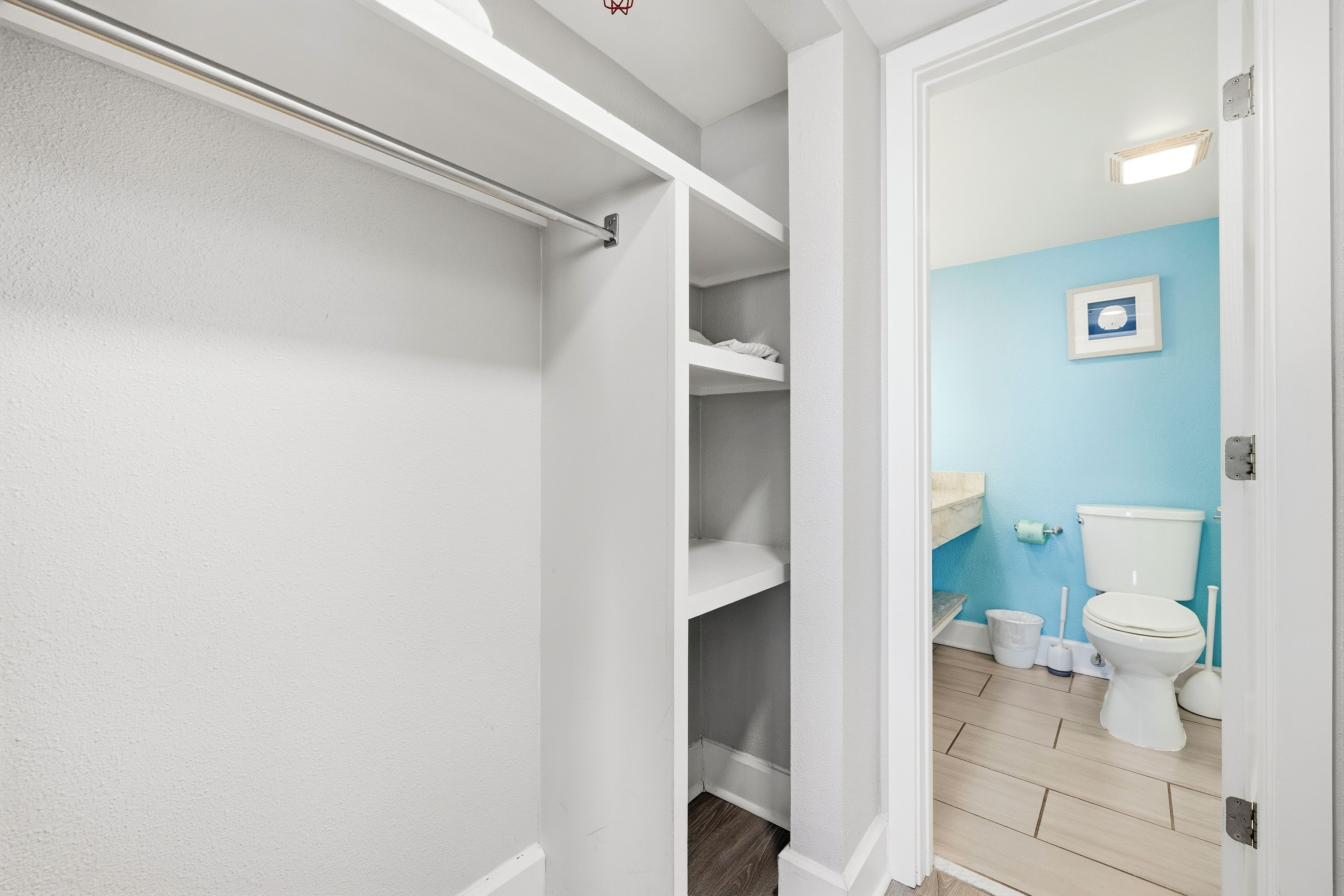 A bathroom with a white toilet, a blue wall, and a white door.