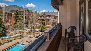 A balcony with a pool view, outdoor seating, and a clear sky. - One-Bedroom Residence (Breckenridge)