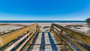 A wooden boardwalk leading to a beach with a clear blue sky.