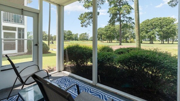 A covered porch with a view of a golf course.