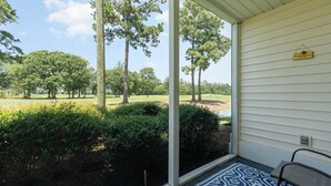 A covered porch with a view of a golf course.