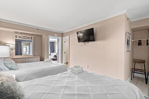 A hotel room with two beds, a TV mounted on the wall, a mirror, and a wardrobe.