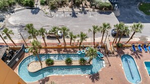 Vue aérienne d’un complexe hôtelier doté d’une grande piscine, de palmiers et d’un parking.