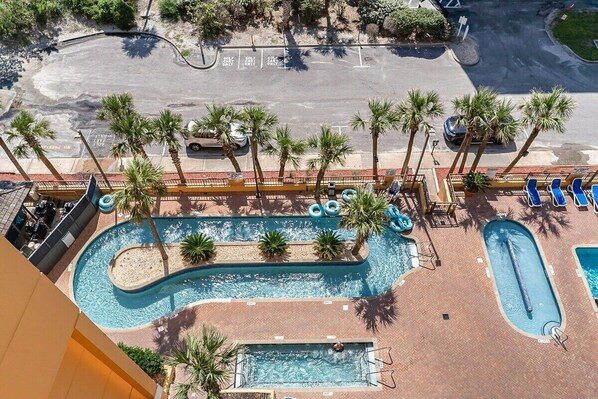 An aerial view of a resort with a large swimming pool, palm trees, and a parking area. - Bright 1BR Oceanview Condo at Caravelle Resort – Pools, Beach & Balcony Views (Myrtle Beach)