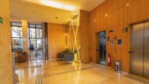 Um hall moderno com parede de madeira, balcão de recepção, área de estar e elevador.