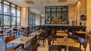 Um restaurante com área de bar, mesas e cadeiras de madeira.