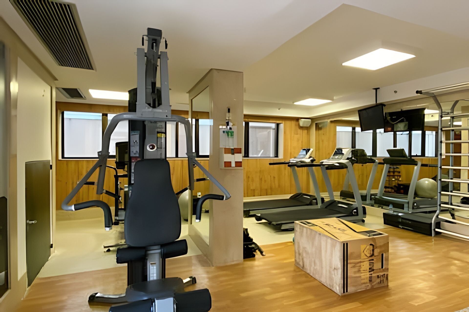 Une salle de sport équipée de matériel d’exercice, de tapis de course et dotée d’un plancher en bois.