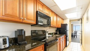 Una cocina con armarios de madera, microondas, cafetera, tostadora y horno.