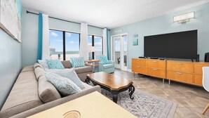 Ein modernes Wohnzimmer mit einer Couch, Sesseln, einem Couchtisch und einem Fernseher.