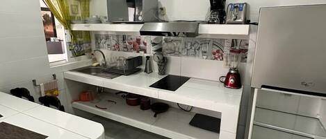 Una cocina moderna con gabinetes blancos, una campana extractora de acero inoxidable, un horno empotrado y una cafetera.