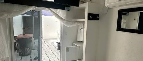 A hotel room with a bed, a TV, an air conditioner, and a sliding door leading to a balcony.