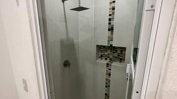 A small, enclosed shower area with a tiled floor and a mosaic tile accent on the wall.