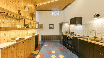 Una cocina con armarios de madera, un refrigerador de acero inoxidable, un lavamanos y un llamativo patrón de suelo hexagonal.