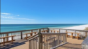 Una terraza de madera con vistas a la playa y al océano.