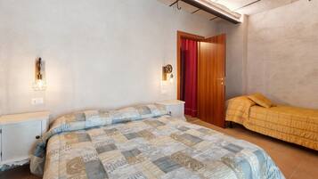 A bedroom with a large bed, a smaller bed, a nightstand, a wardrobe, and a red curtain.