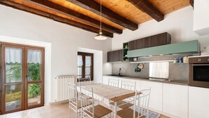 A modern kitchen with white cabinets, a wooden ceiling, and a dining area with a table and chairs. - Holiday Home 'Casa Vacanze Laghi e Monti' with Mountain View, Private Garden and Wi-Fi (Mergozzo)