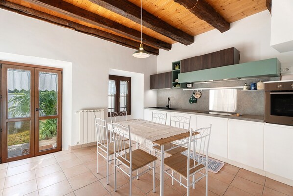 A modern kitchen with white cabinets, a wooden ceiling, and a dining area with a table and chairs.