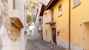A narrow street with buildings on either side, featuring a mix of architectural styles and a visible door on the right. - Holiday Home 'Casa Vacanze Laghi e Monti' with Mountain View, Private Garden and Wi-Fi (Mergozzo)