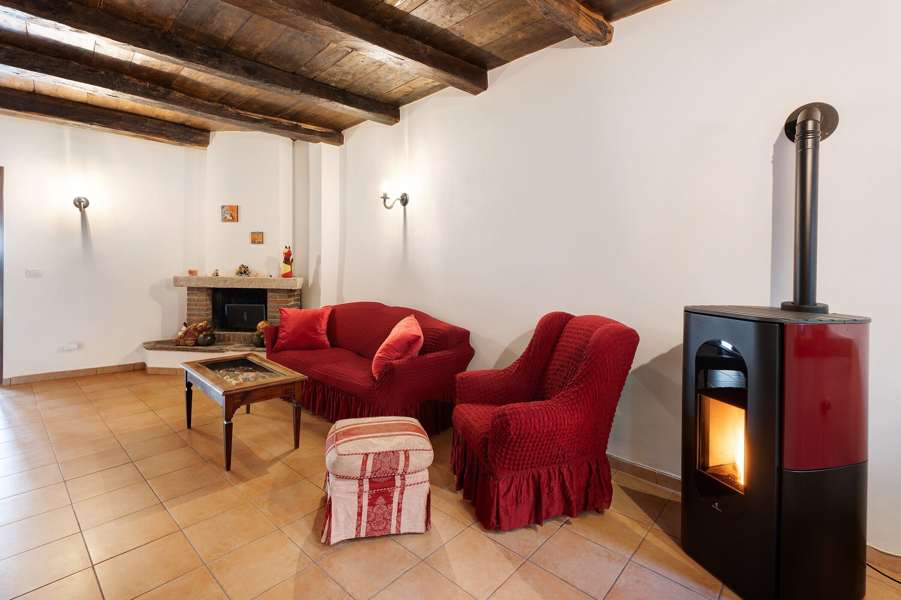 A living room with a fireplace, red furniture, and a tiled floor.