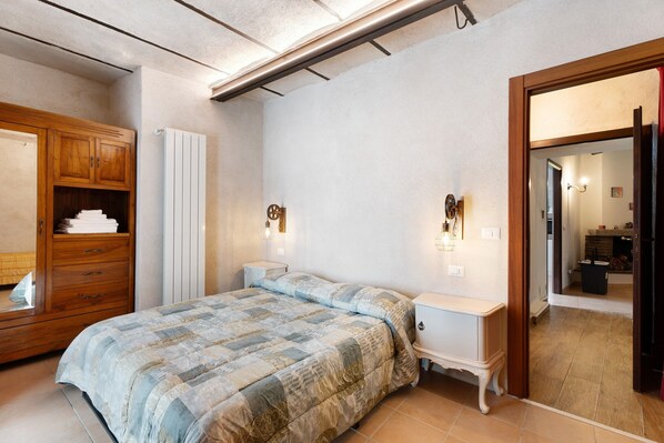 Ein Schlafzimmer mit einem Bett, einem Holzschrank, Nachttischen und einem Spiegel.