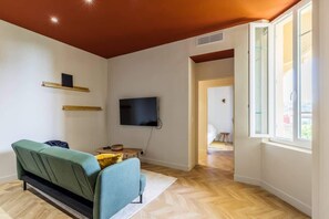 A modern living room with a sofa, television, and wooden flooring.