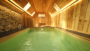A wooden interior with a swimming pool, stone wall, and skylights. - Gite Finistère for 7: Private Pool & Spa, Garden, 4 km from Beaches (PEUMERIT)